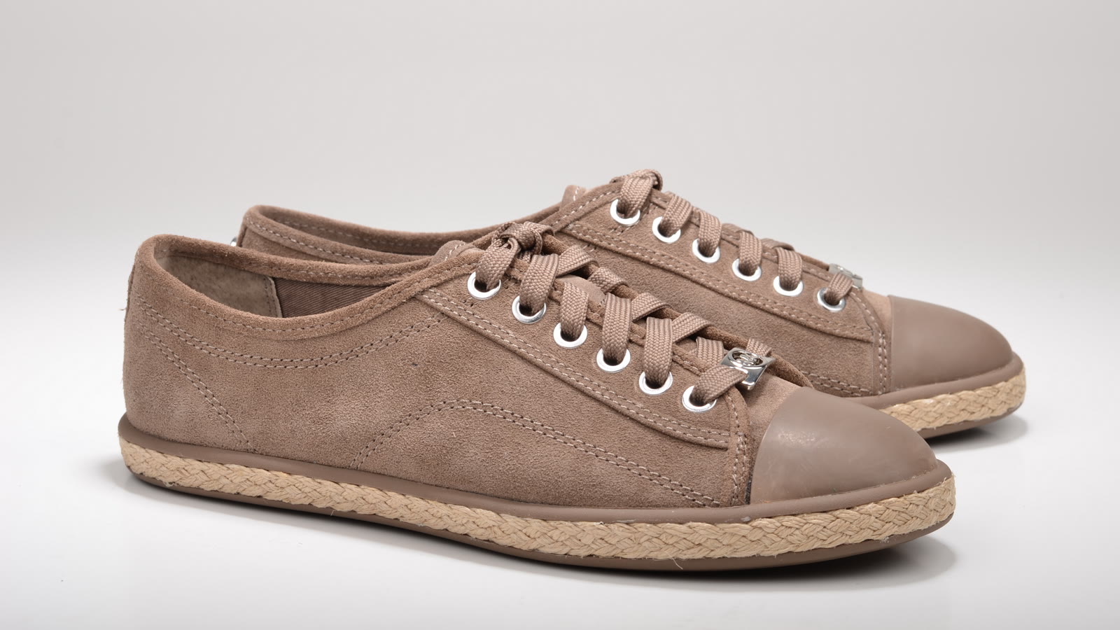 A pair of brown suede sneakers photographed on a white studio background