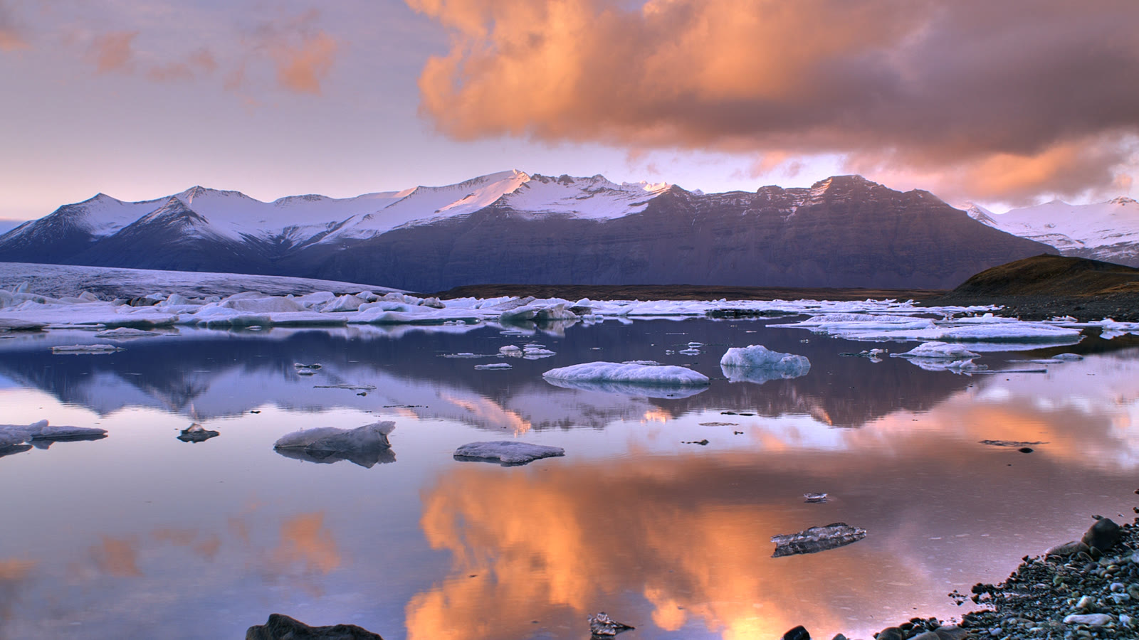 Icebergs drifting across a glacier lagoon at sunset in Iceland